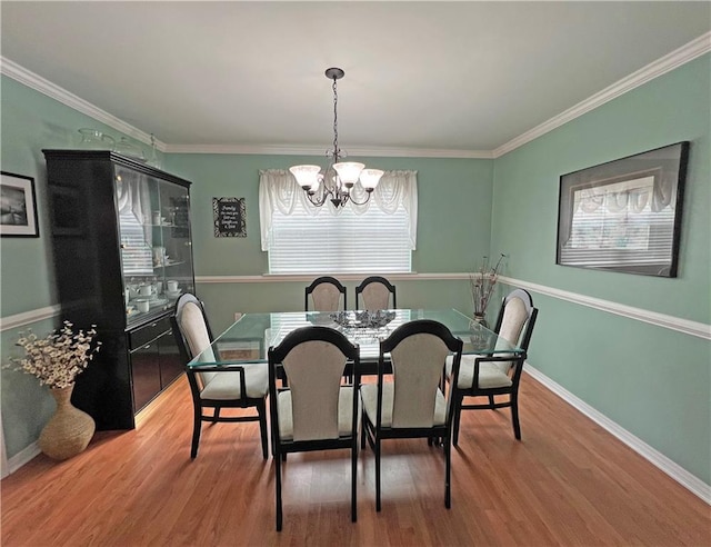 dining room with a notable chandelier, crown molding, and hardwood / wood-style floors