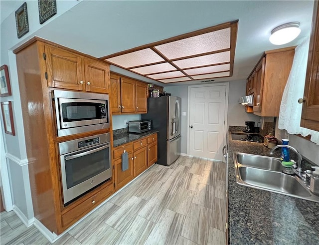 kitchen featuring stainless steel appliances, sink, and dark stone counters