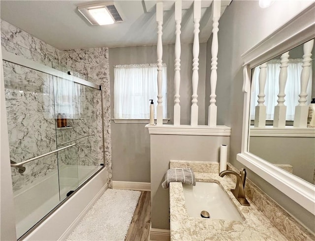 bathroom featuring bath / shower combo with glass door, vanity, and wood-type flooring