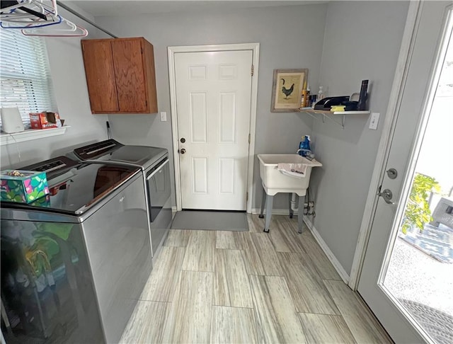 laundry room featuring light wood-type flooring, cabinets, and washer and clothes dryer