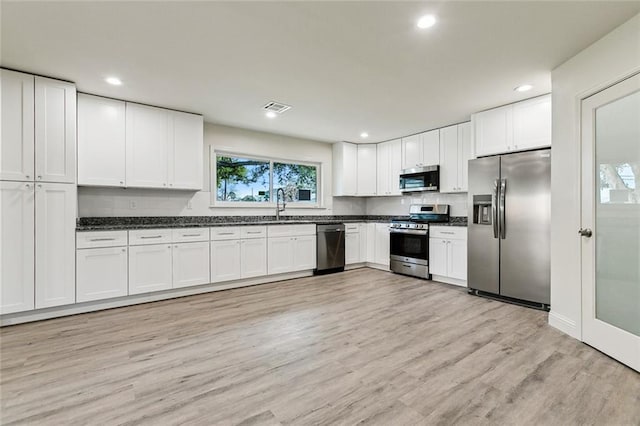 kitchen featuring appliances with stainless steel finishes, white cabinetry, sink, and light hardwood / wood-style floors