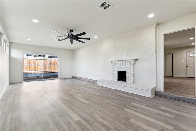 unfurnished living room featuring a brick fireplace, ceiling fan, and light hardwood / wood-style floors