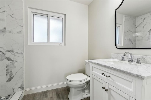 bathroom featuring toilet, tiled shower, wood-type flooring, and vanity