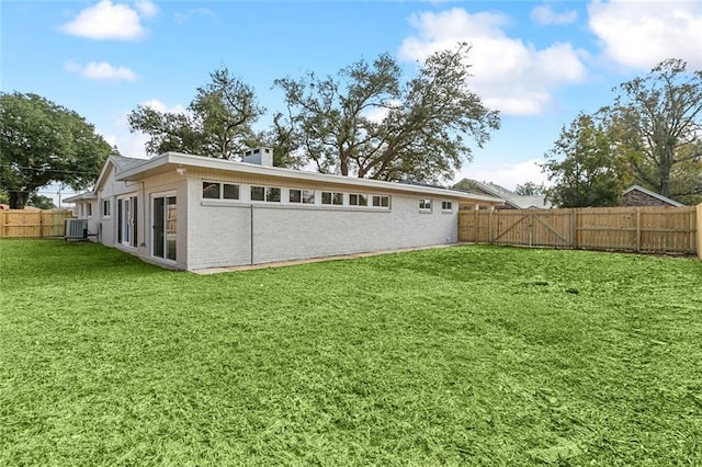 rear view of property featuring cooling unit and a yard