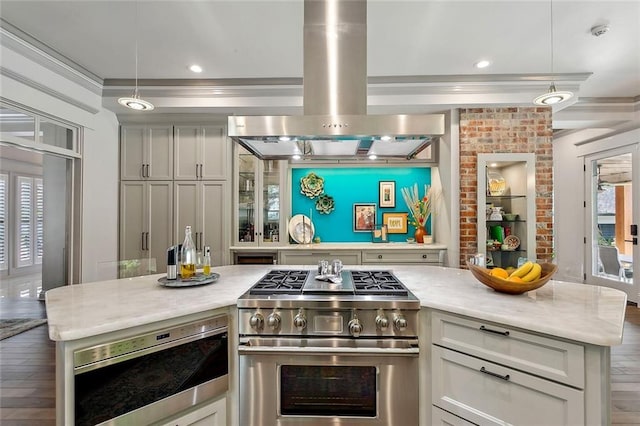 kitchen featuring pendant lighting, hardwood / wood-style flooring, stainless steel appliances, ornamental molding, and island exhaust hood