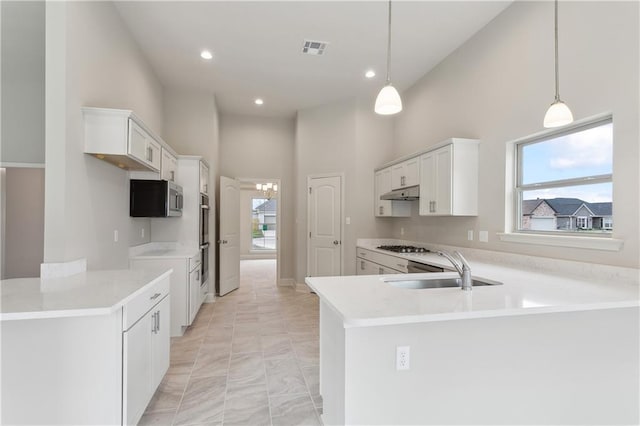 kitchen featuring kitchen peninsula, stainless steel appliances, white cabinets, and hanging light fixtures