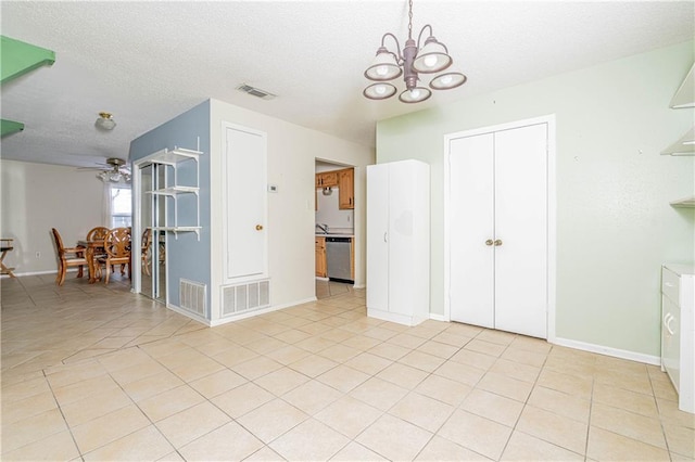 tiled spare room with ceiling fan with notable chandelier and a textured ceiling