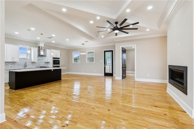 unfurnished living room with ornamental molding, ceiling fan, light wood-type flooring, and beamed ceiling