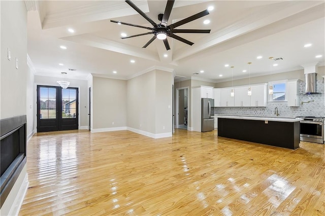 unfurnished living room with ceiling fan, light hardwood / wood-style flooring, ornamental molding, and sink