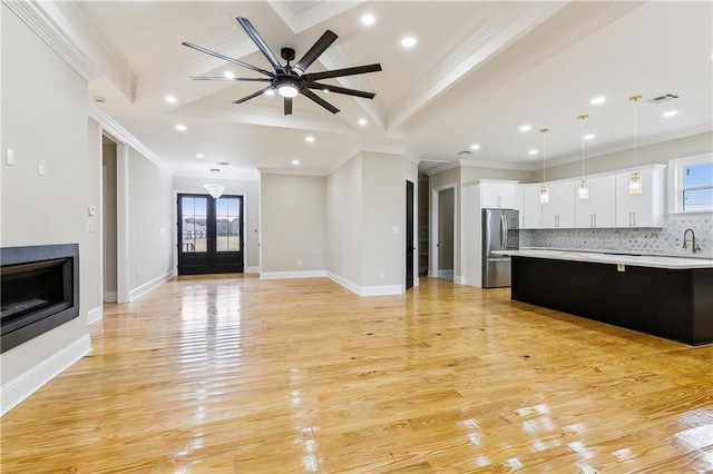 unfurnished living room with ornamental molding, ceiling fan, sink, and plenty of natural light