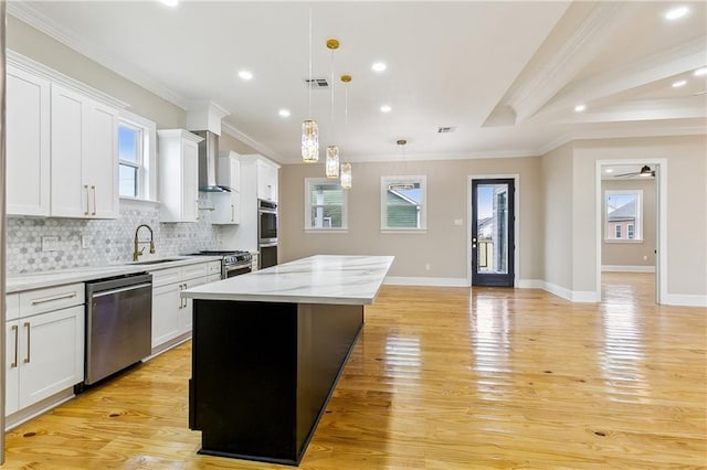 kitchen with appliances with stainless steel finishes, pendant lighting, white cabinetry, and a kitchen island