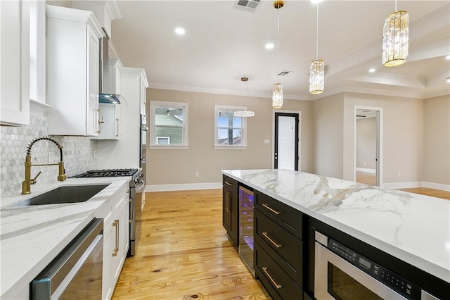 kitchen with stainless steel appliances, white cabinets, decorative light fixtures, and sink