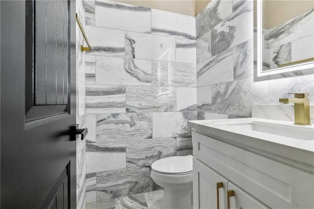 bathroom with tile walls, walk in shower, vanity, and toilet