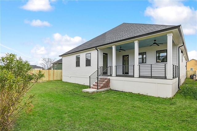 rear view of property with ceiling fan, a yard, and a porch