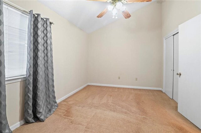 carpeted empty room with ceiling fan and lofted ceiling