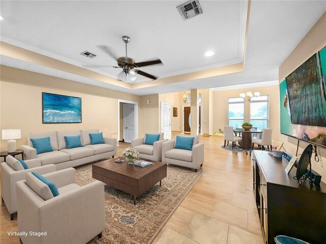 living room featuring crown molding, a raised ceiling, and ceiling fan with notable chandelier