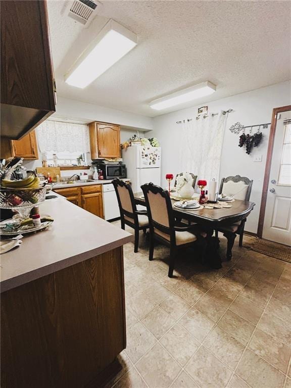 kitchen with white appliances, a textured ceiling, and sink