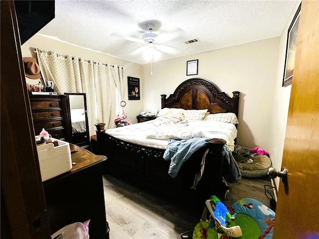 bedroom featuring ceiling fan, light hardwood / wood-style flooring, and a textured ceiling