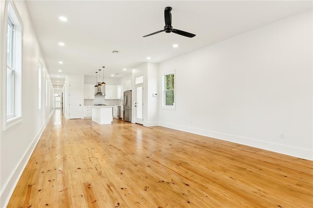 unfurnished living room featuring light wood-type flooring and ceiling fan