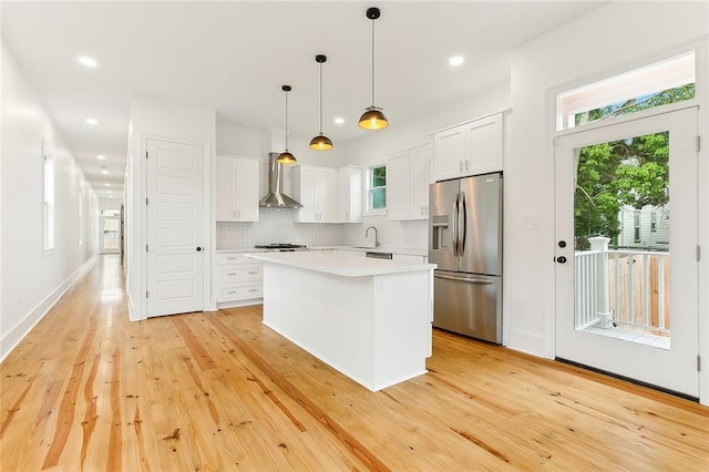 kitchen with decorative light fixtures, stainless steel fridge, decorative backsplash, a kitchen island, and white cabinets