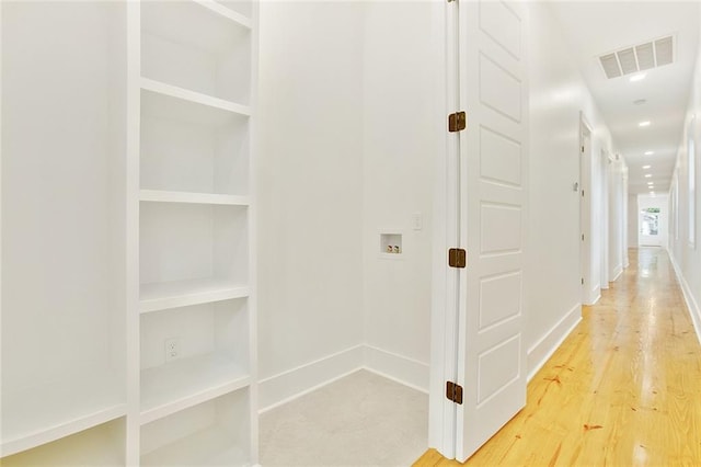 hall featuring built in shelves and wood-type flooring