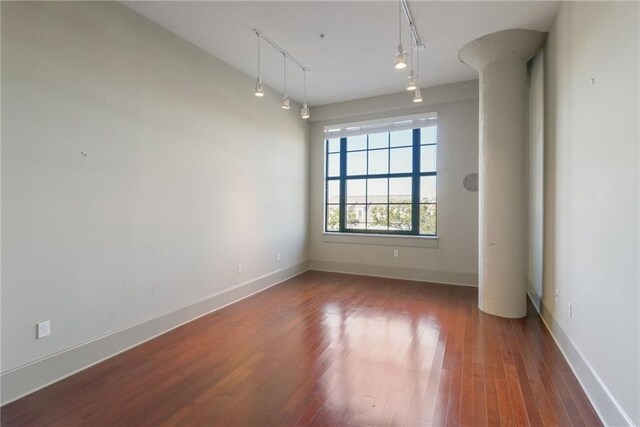 empty room featuring rail lighting and dark hardwood / wood-style floors