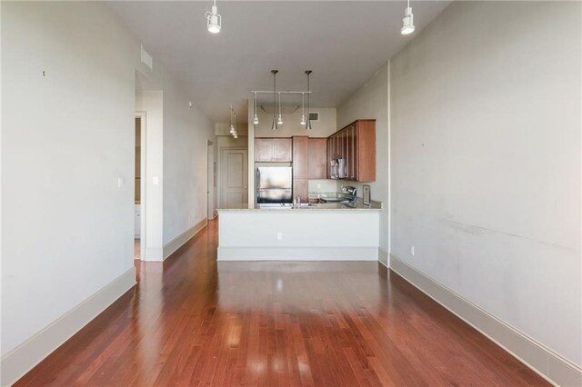 kitchen featuring kitchen peninsula, dark wood-type flooring, hanging light fixtures, appliances with stainless steel finishes, and sink