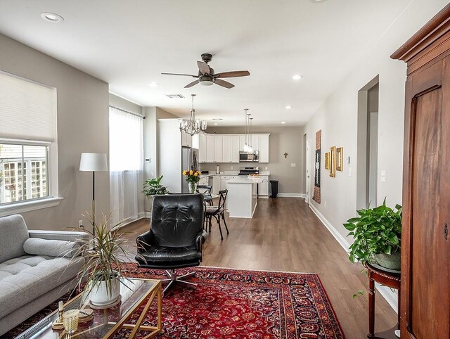 living room featuring ceiling fan with notable chandelier and hardwood / wood-style flooring