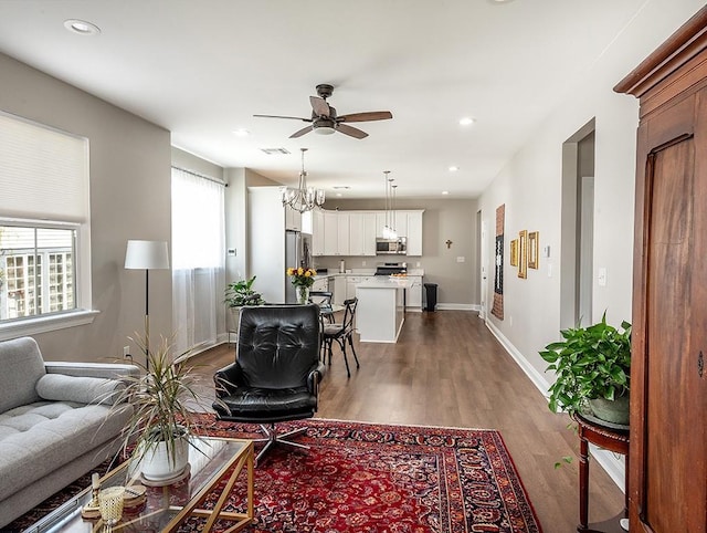 living room with ceiling fan with notable chandelier and hardwood / wood-style floors