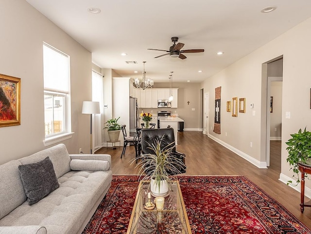 living room featuring ceiling fan with notable chandelier and wood-type flooring