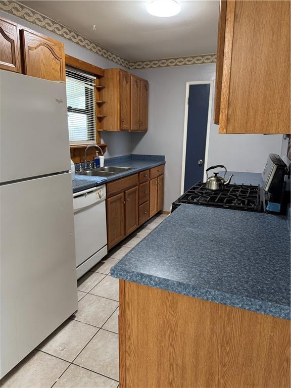 756 Mystic Ave, Gretna, LA 70056 - kitchen featuring dark countertops, white appliances, brown cabinetry, and a sink
