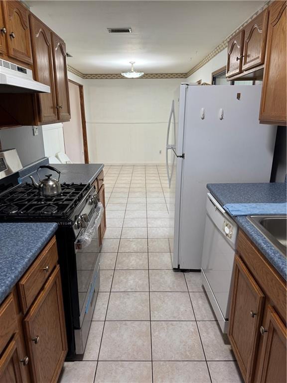 756 Mystic Ave, Gretna, LA 70056 - kitchen featuring under cabinet range hood, light tile patterned floors, dark countertops, gas range oven, and dishwasher