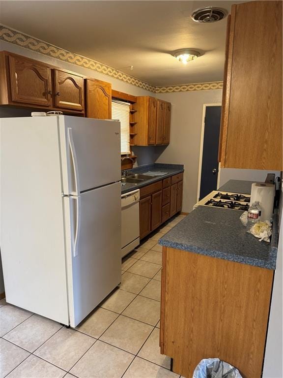 kitchen with sink, white appliances, and light tile patterned floors