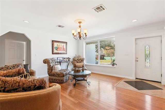 living area featuring crown molding, a notable chandelier, and light wood-type flooring