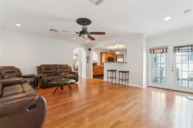 living room featuring ceiling fan, ornamental molding, and light hardwood / wood-style floors