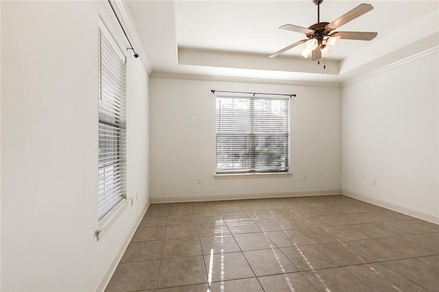 spare room with ceiling fan, tile patterned floors, and a tray ceiling