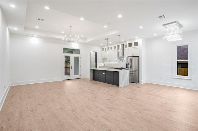 kitchen with a large island with sink, white cabinets, pendant lighting, stainless steel refrigerator with ice dispenser, and an inviting chandelier