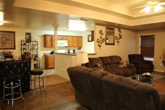 living room featuring ceiling fan, a tray ceiling, and hardwood / wood-style flooring