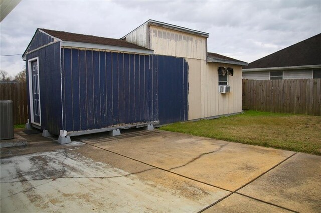 view of property exterior with a patio area, cooling unit, an outbuilding, central AC, and a yard