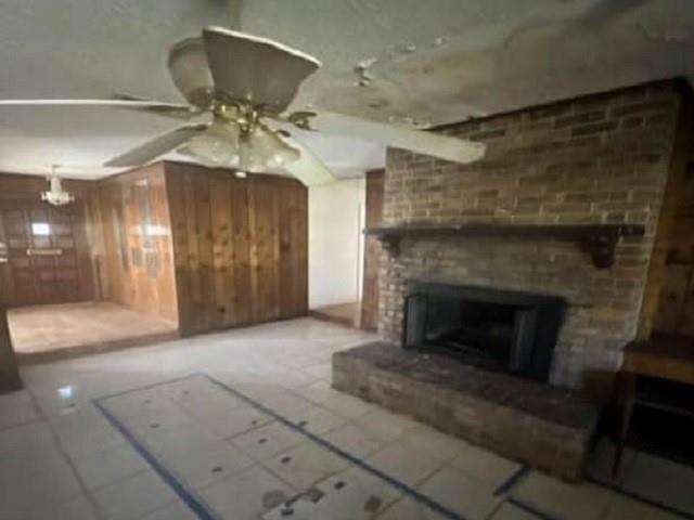 unfurnished living room featuring ceiling fan and wooden walls