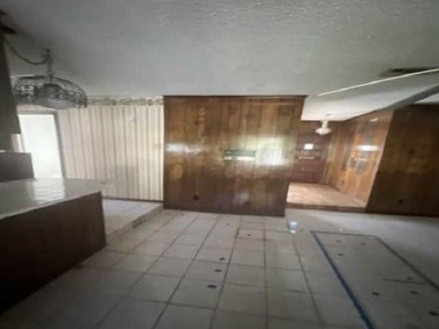 interior space featuring tile patterned flooring and wooden walls