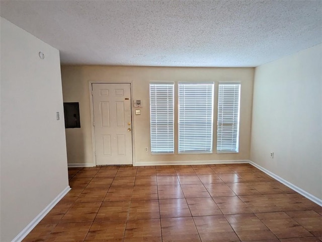 foyer entrance with electric panel, a textured ceiling, and baseboards