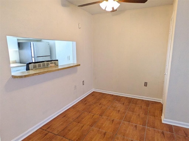 spare room with a ceiling fan, wood finished floors, and baseboards