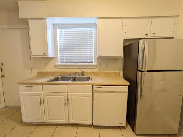 kitchen with a sink, freestanding refrigerator, white cabinets, light countertops, and dishwasher