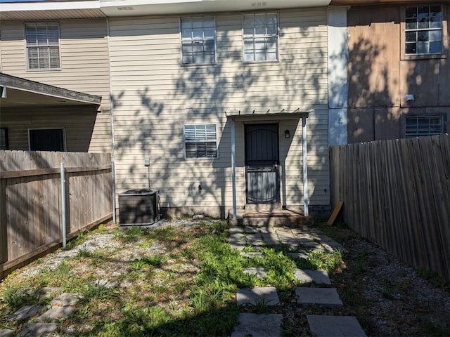 view of exterior entry featuring central AC and fence