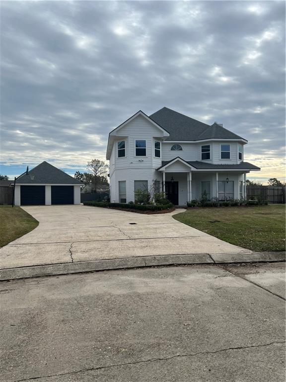 traditional home featuring an outbuilding, fence, a detached garage, and a front lawn