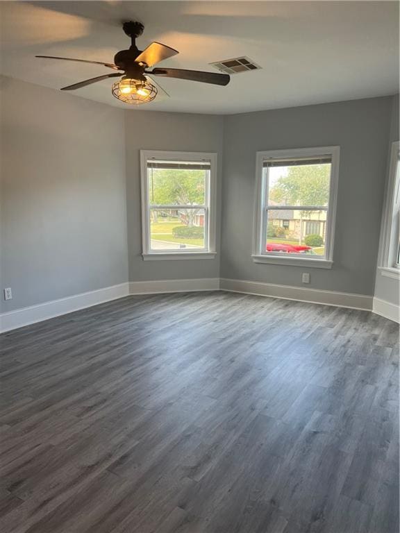 unfurnished room with a ceiling fan, baseboards, visible vents, and dark wood-style flooring