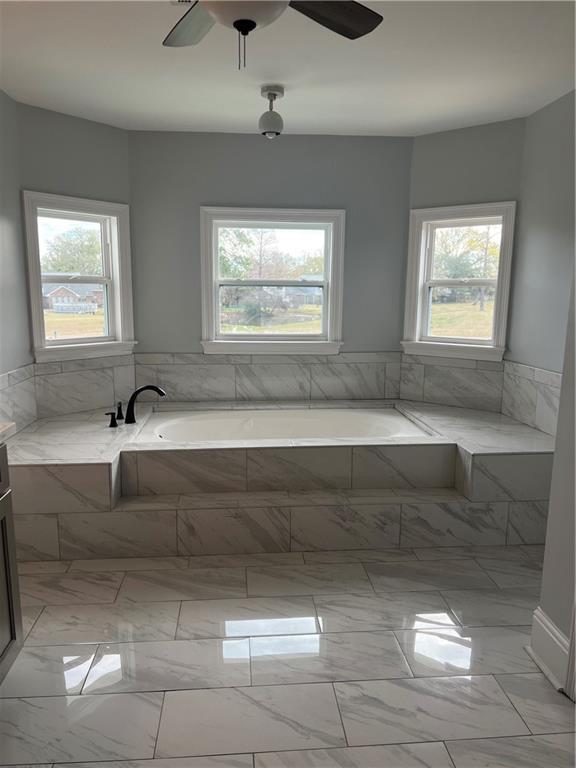 bathroom featuring a ceiling fan, marble finish floor, and a garden tub