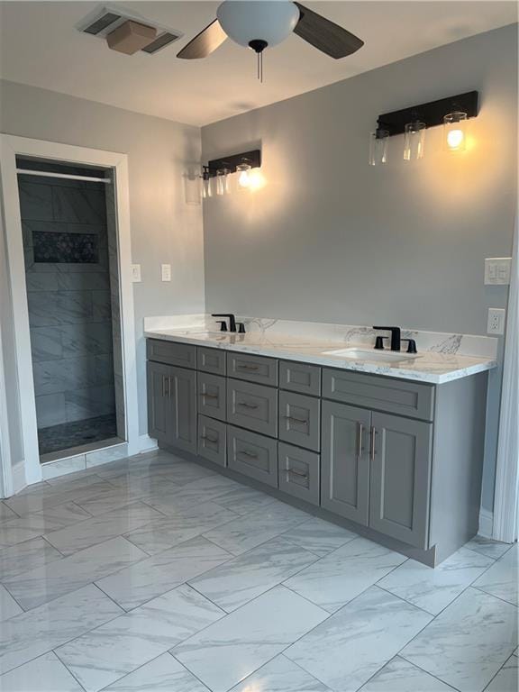 bathroom featuring marble finish floor, visible vents, a ceiling fan, a sink, and a tile shower