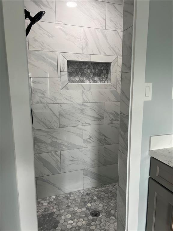 bathroom featuring a tile shower and vanity